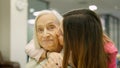 Smiling nurse kissing and embracing a senior woman in geriatrics