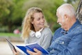 Smiling nurse reading book to senior man outdoor Royalty Free Stock Photo