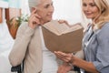 smiling nurse reading book to senior patient Royalty Free Stock Photo