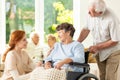 Smiling nurse and senior man supporting paralyzed elderly woman