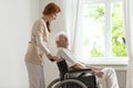 Smiling nurse supporting disabled senior man in the wheelchair