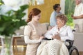 Smiling nurse taking care of happy paralyzed senior woman in the Royalty Free Stock Photo