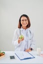 Smiling nutritionist in her office, she is showing healthy vegetables and fruits, healthcare and diet concept Royalty Free Stock Photo