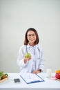 Smiling nutritionist in her office, she is showing healthy vegetables and fruits, healthcare and diet concept Royalty Free Stock Photo