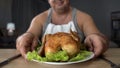 Smiling obese male looking at fatty grilled chicken, overeating and junk food