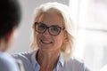 Smiling old businesswoman looking at colleague listening client at meeting Royalty Free Stock Photo