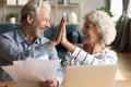 Smiling old hoary man giving high five to mature wife.