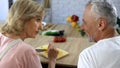 Smiling old husband looking at wife cooking dinner at home kitchen, family Royalty Free Stock Photo