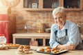 Smiling old lady posing with freshly baked pastry in kitchen Royalty Free Stock Photo