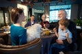 Smiling old man with glass of wine while celebrating Christmas in restaurant