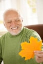 Smiling old man looking at yellow leaf