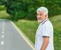 Smiling old man standing on city`s racetrack looking at camera. Royalty Free Stock Photo