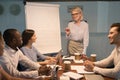 Smiling old coach giving presentation on flipchart training young employees Royalty Free Stock Photo