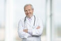 Smiling old medical doctor with crossed arms standing. Royalty Free Stock Photo