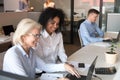 Smiling old mentor helping african intern with laptop in office Royalty Free Stock Photo