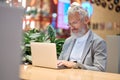 Smiling old senior business man using laptop working late on computer. Royalty Free Stock Photo