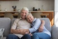 Loving older couple hugging relaxing on sofa looking at camera Royalty Free Stock Photo