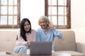 Smiling older mother and adult daughter using phone together, sitting on cozy sofa at home, happy young woman and mature Royalty Free Stock Photo