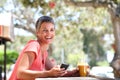 Smiling older woman sitting outside with mobile phone and drink Royalty Free Stock Photo