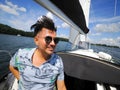 Smiling one adult person on a sailboat during his yacht voyage in a sunny summer day