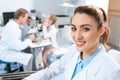 smiling ophthalmologist holding lenses for trial frame while colleague examining kid with visual