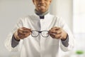 Smiling optician holds new good quality eyeglasses and suggests you try them on Royalty Free Stock Photo