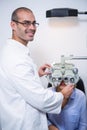 Smiling optometrist examining female patient on phoropter