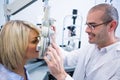 Smiling optometrist examining female patient on phoropter