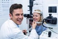 Smiling optometrist examining female patient on slit lamp