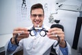 Smiling optometrist holding messbrille