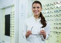 Smiling optometrist holding spectacles in optical store