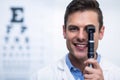 Smiling optometrist looking through ophthalmoscope