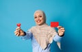 Smiling oriental woman in hijab showing a shape of red heart and blank red plastic card