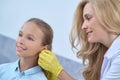 Smiling otolaryngologist examining ear of school age girl