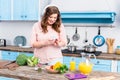 smiling overweight woman in headphones using smartphone at table with fresh vegetables in kitchen Royalty Free Stock Photo