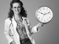 Smiling paediatrician doctor showing clock on