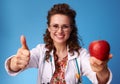 Paediatrician doctor giving an apple and showing thumbs up Royalty Free Stock Photo