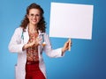 Smiling paediatrician woman pointing at placard on blue
