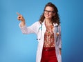 Smiling paediatrician woman pointing at something on blue