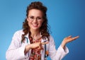 Smiling paediatrician woman pointing on something on empty palm Royalty Free Stock Photo