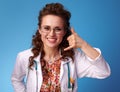 Smiling paediatrist woman showing call me gesture on blue Royalty Free Stock Photo