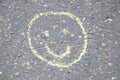 Smiling painted face with colorful chalks on asphalt, smiley sign sketched outdoor by children while walking