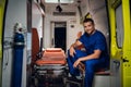 Smiling paramedic in a blue uniform sitting in the back of an ambulance car Royalty Free Stock Photo