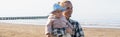 Smiling parent holding toddler kid on beach near adriatic sea in Italy, banner,stock image