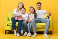 Parents and kids watching movie on sofa with popcorn bucket on yellow Royalty Free Stock Photo