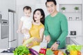 Smiling parents and little girl cook vegetables