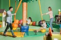 smiling parents looking at happy kids swinging on swings in indoor Royalty Free Stock Photo