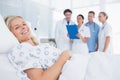 Smiling patient looking at camera with doctors behind Royalty Free Stock Photo