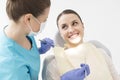 Smiling patient looking at dentist with angled mirror and scaler at clinic