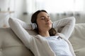 Smiling peaceful woman listening to favorite audio music in earphones.